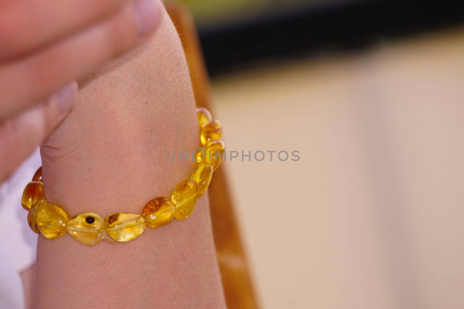 Amber bracelet on woman hand close up view by tasci