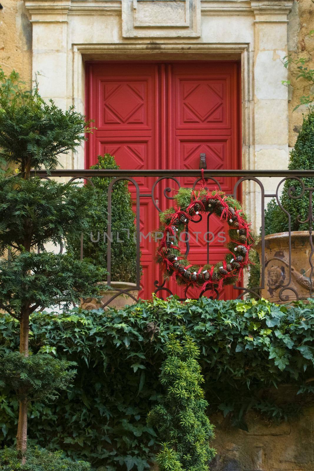 Red door with wreath of Christmas tree branches and cones