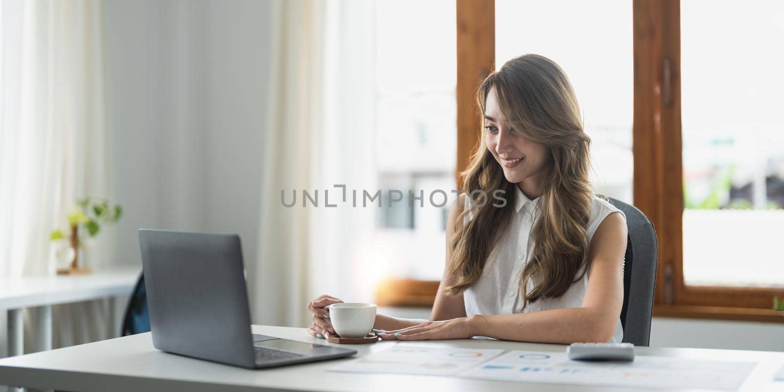 Happy asian woman sit at table busy in personal expenses management, use calculator calculate household utilities, pay bills through secure e-banking app on laptop. Finances, accounting concept.