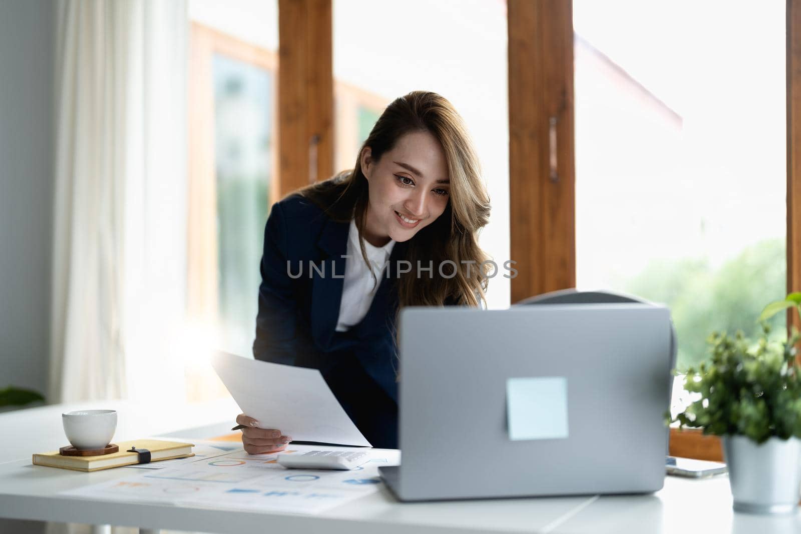 Portrait of an asian young business Female working on a laptop computer with financial report in her workstation. Business people employee freelance online report marketing e-commerce financial concept