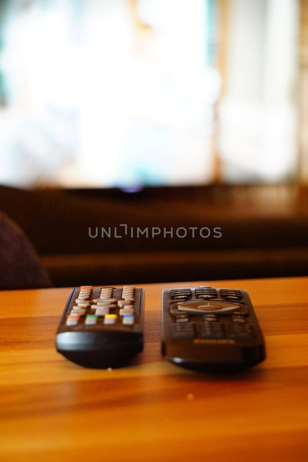 Two television remote controllers on wooden background image with shallow depth of field