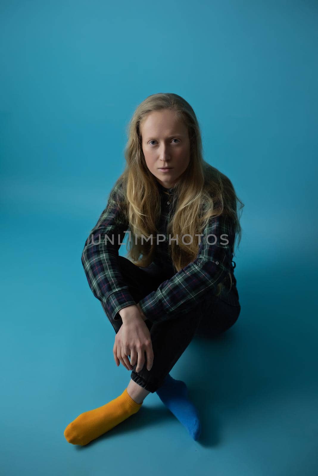 A young Ukrainian woman on an isolated blue background in the studio. Modern blonde in yellow blue socks during the war in Ukraine for the support of peace