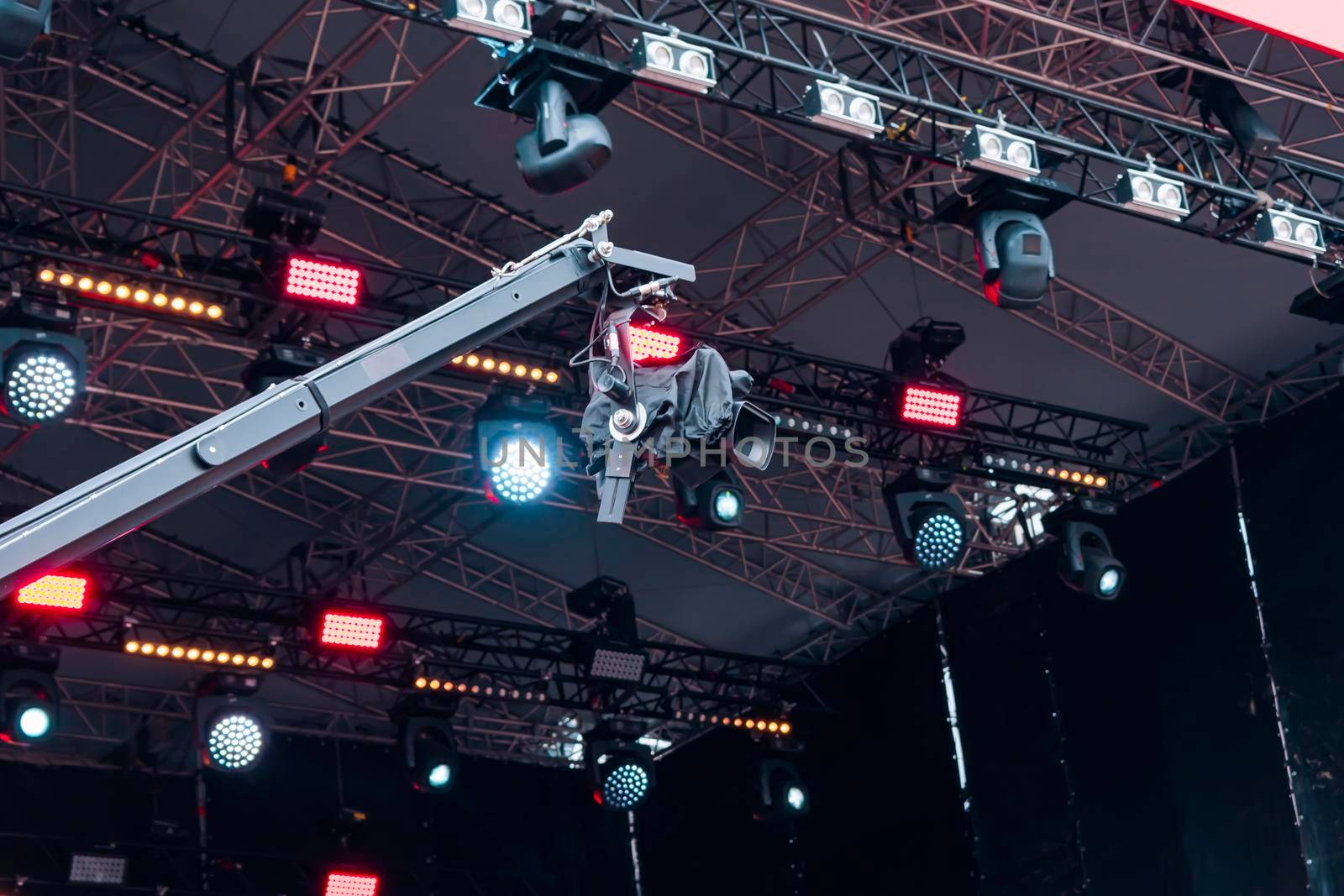 Movie camera filming a musical concert on the background of stage spotlights