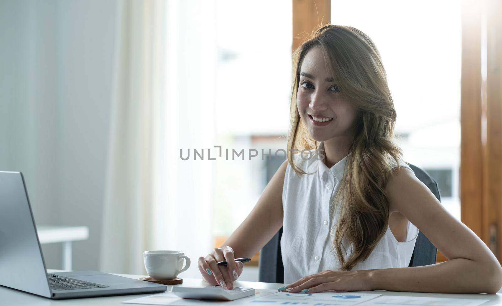 Charming Asian woman working at the office using a laptop Looking at the camera..