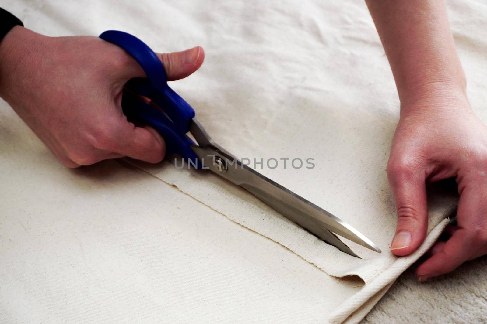 Woman measuring and cutting fabric at home close up view