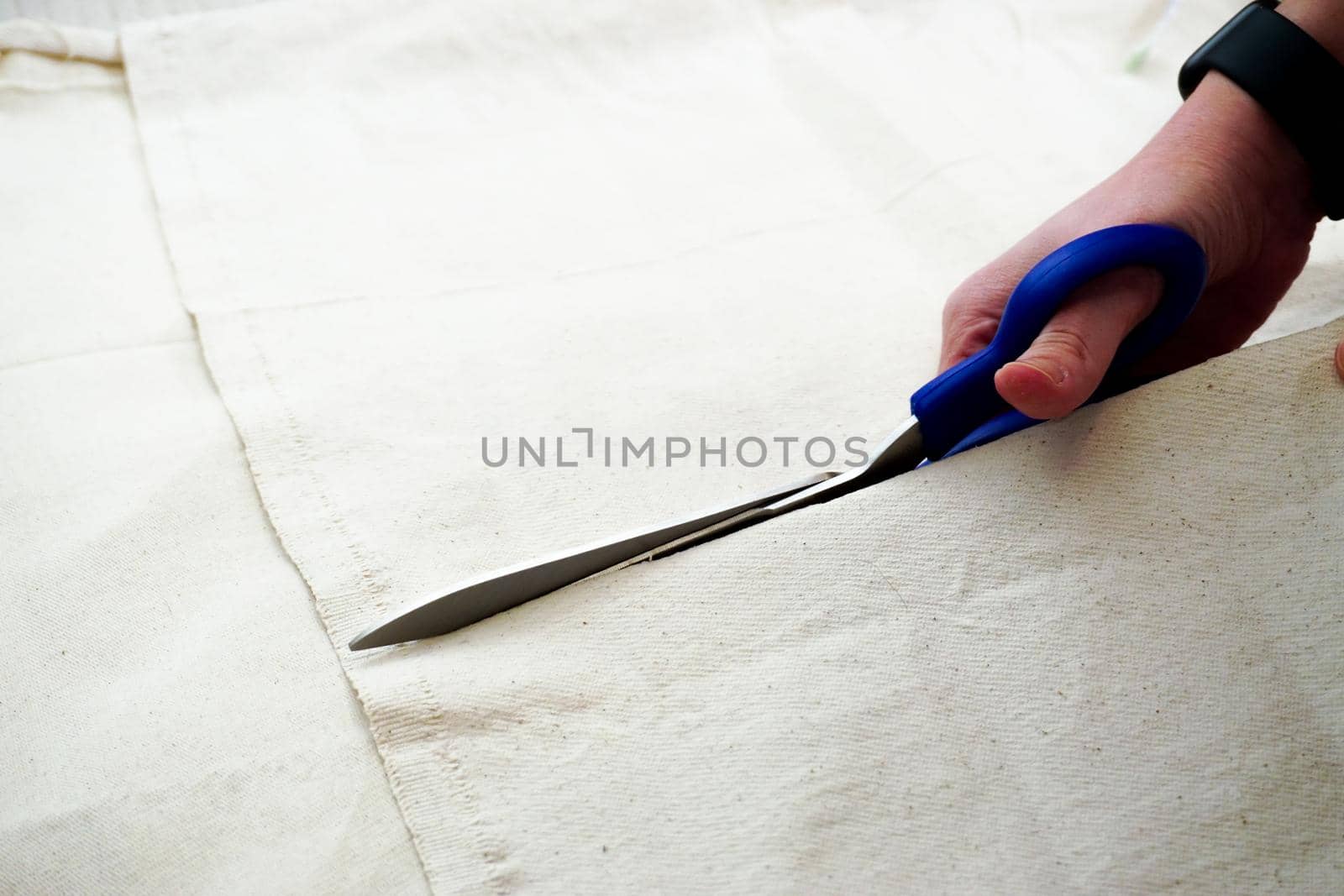 Woman measuring and cutting fabric at home close up view