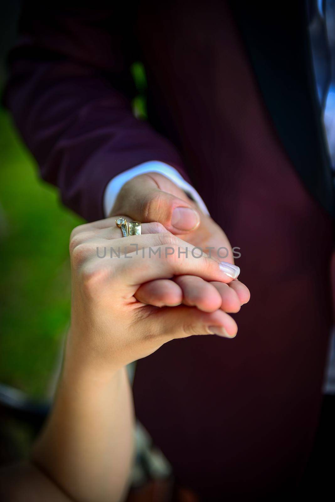 Bride and groom holding hands with engagement rings on their fingers close up view wedding shoot concept