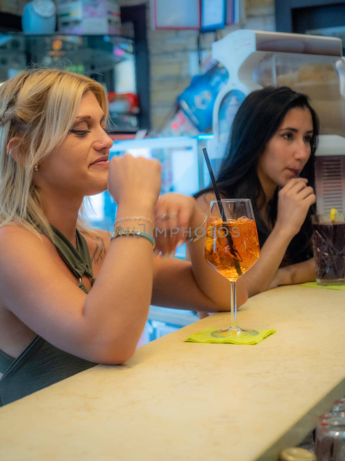 women friends drinking cocktails at the bar counter having good time
