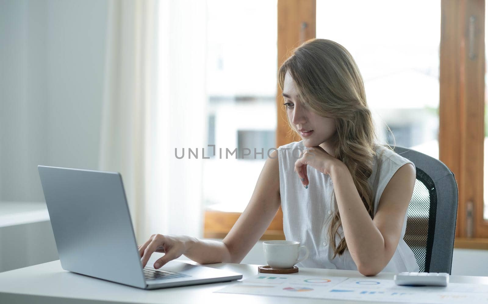 Smiling asian business woman sitting in a modern office. by wichayada