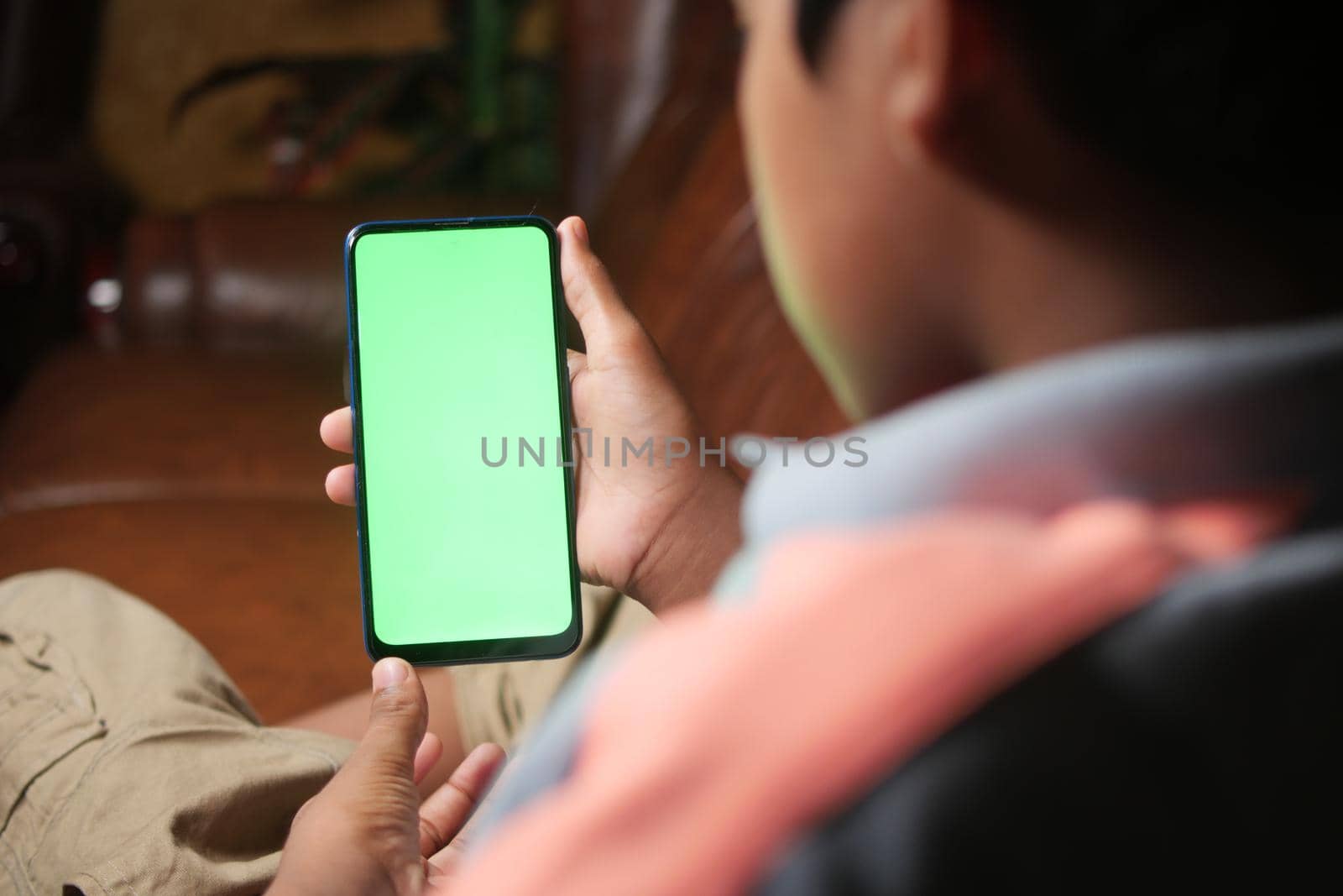 teenage boy sitting on sofa using smart phone at night .