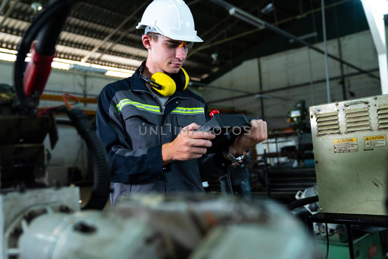 Young factory worker working with adept robotic arm in a workshop . Industry robot programming software for automated manufacturing technology .