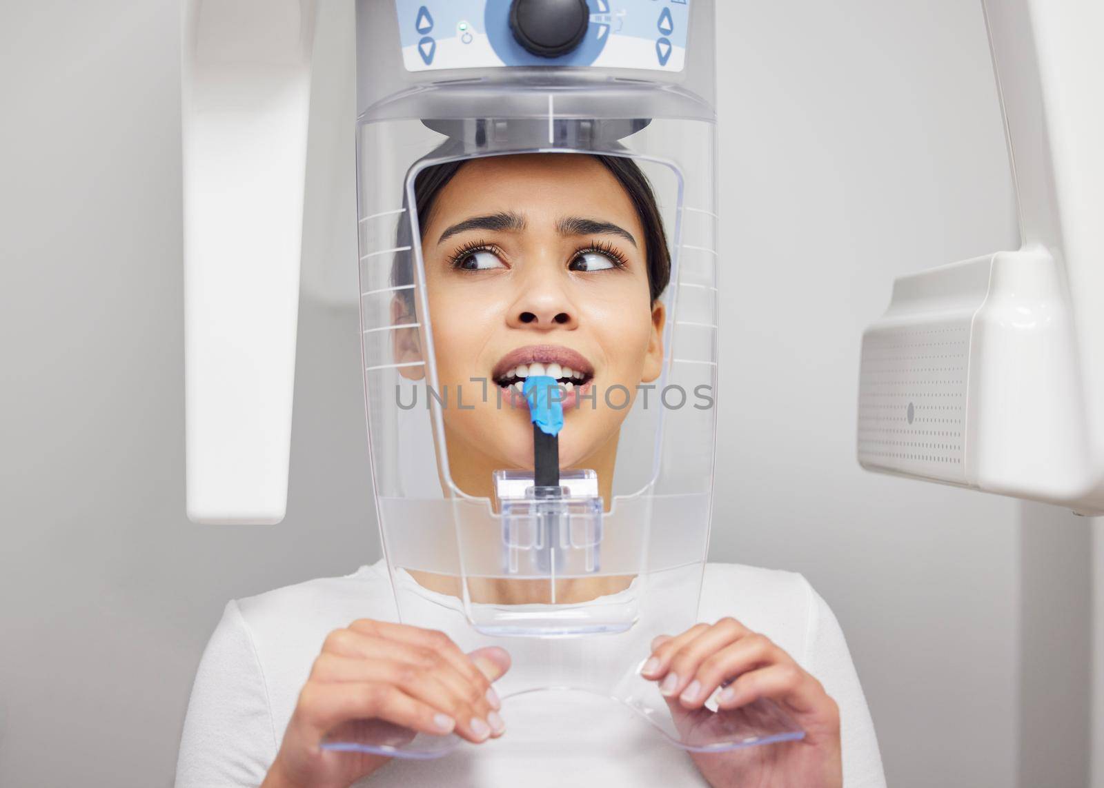 Why is this thing making that noise. a young woman looking anxious while using an x ray machine at a dentists office. by YuriArcurs