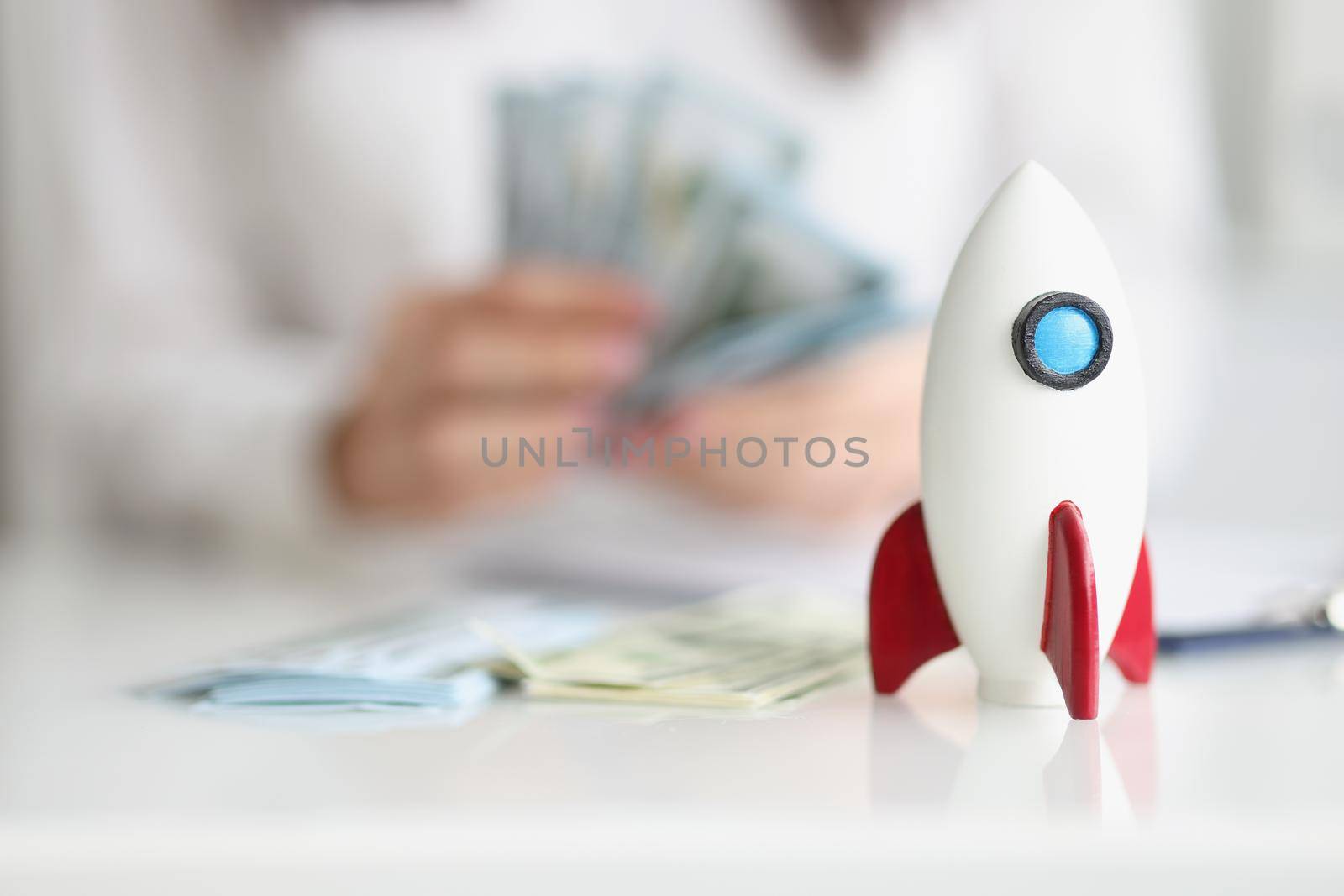Close-up of rocket model on desk, rocketship symbol for startup, earn money on beneficial project. Success, growth, development, wealth, income concept