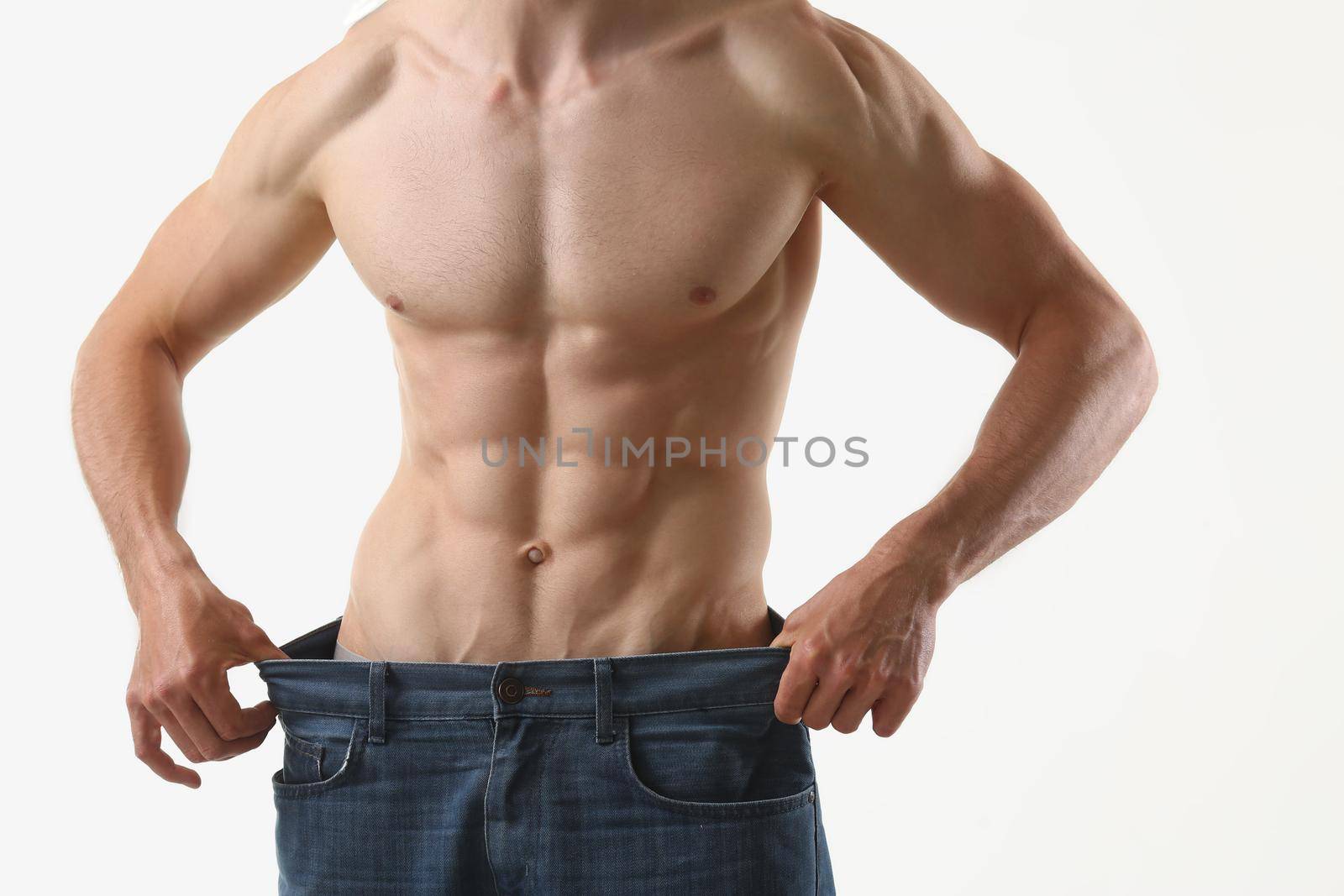 Close-up of fit man with muscles, show how big pants, slim body, perfect figure. Fitness trainer, professional model. Sport, modeling, wellness concept