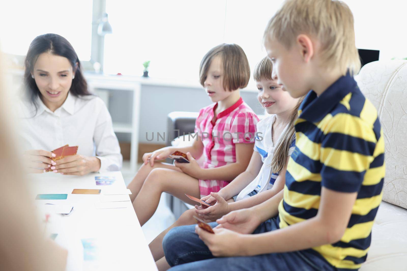 Portrait of children hold playing cards, game with parents at home, games for development. Education, weekend, parenthood, childhood, indoor fun concept