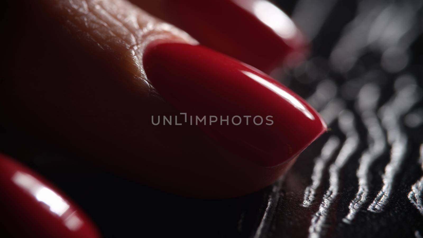 Stylish beautiful red nails on dark background. Classic graceful manicure concept