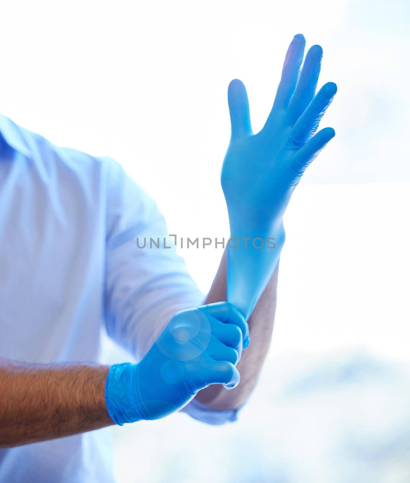 Get those gloves on and get to work. an unrecognisable dentist putting on rubber gloves. by YuriArcurs