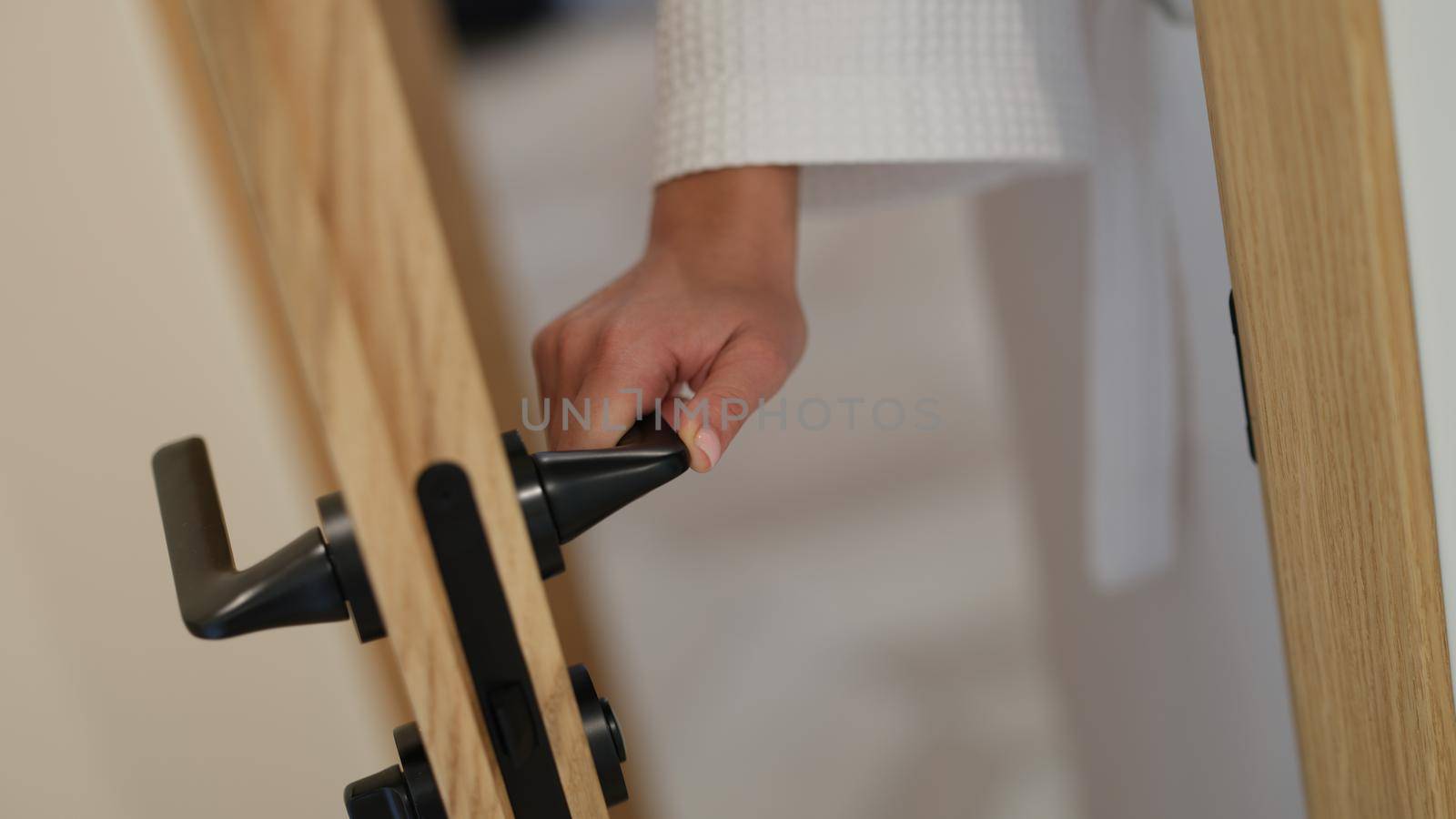 Woman hand in bathrobe opens and closes bathroom door. Services of spa hotels and quality services