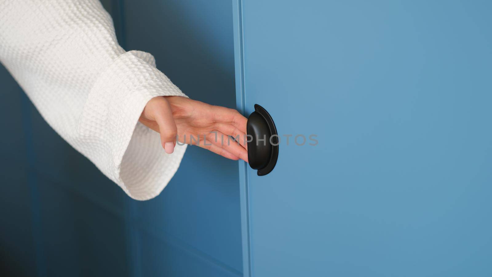 Woman hand opens blue closet door panel or modern closet door. Handle and furniture design concept