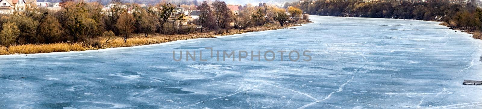 The river is covered with ice in winter. Panorama. Frozen water in the river. Beautiful landscape