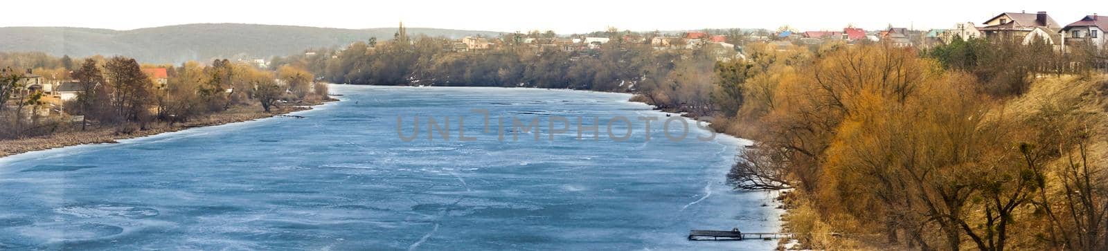 The river is covered with ice in winter. Panorama. Frozen water in the river. Beautiful landscape