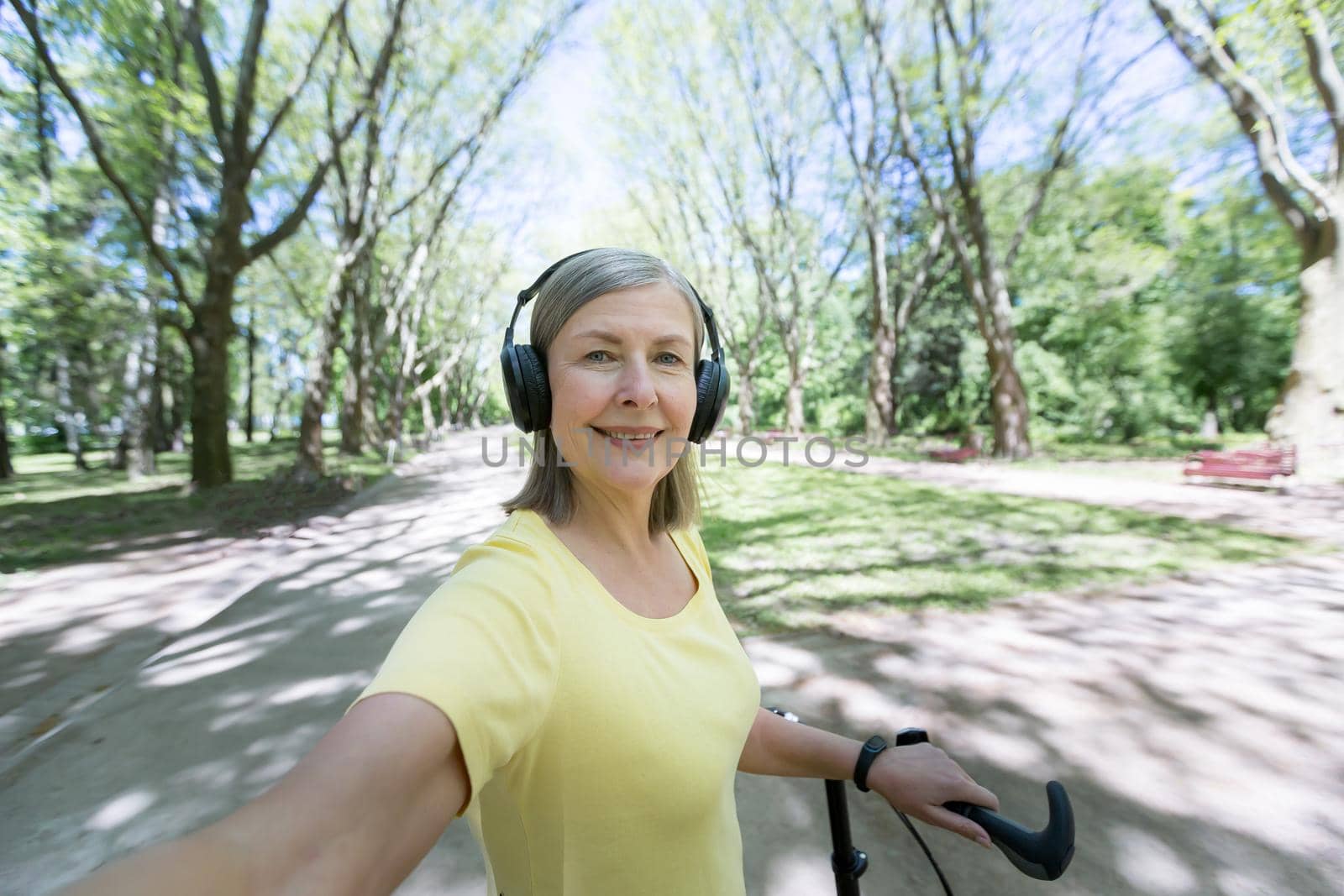 Active pensioner on a morning jog in the park, listening to music from headphones by voronaman
