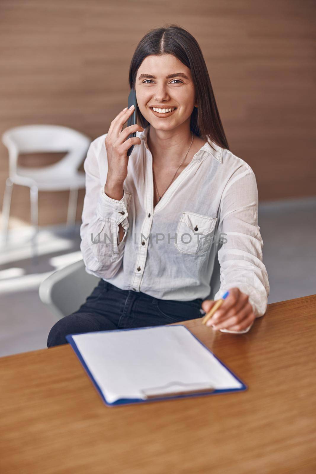 Happy smiling caucasian woman with phone and documents in modern clinic reception