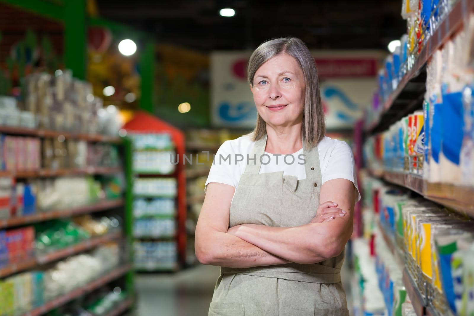 Portrait of happy senior woman grocery store employee with arms crossed smiling by voronaman