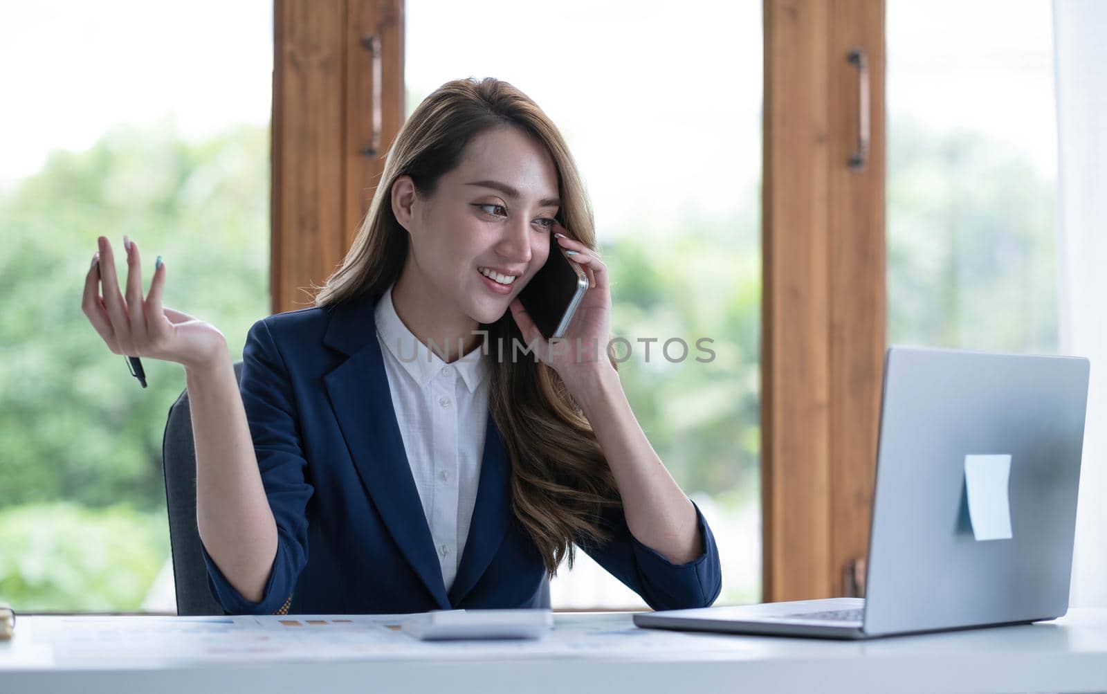 Beautiful young Asian businesswoman charming smiling and talking on the mobile phone in the office..