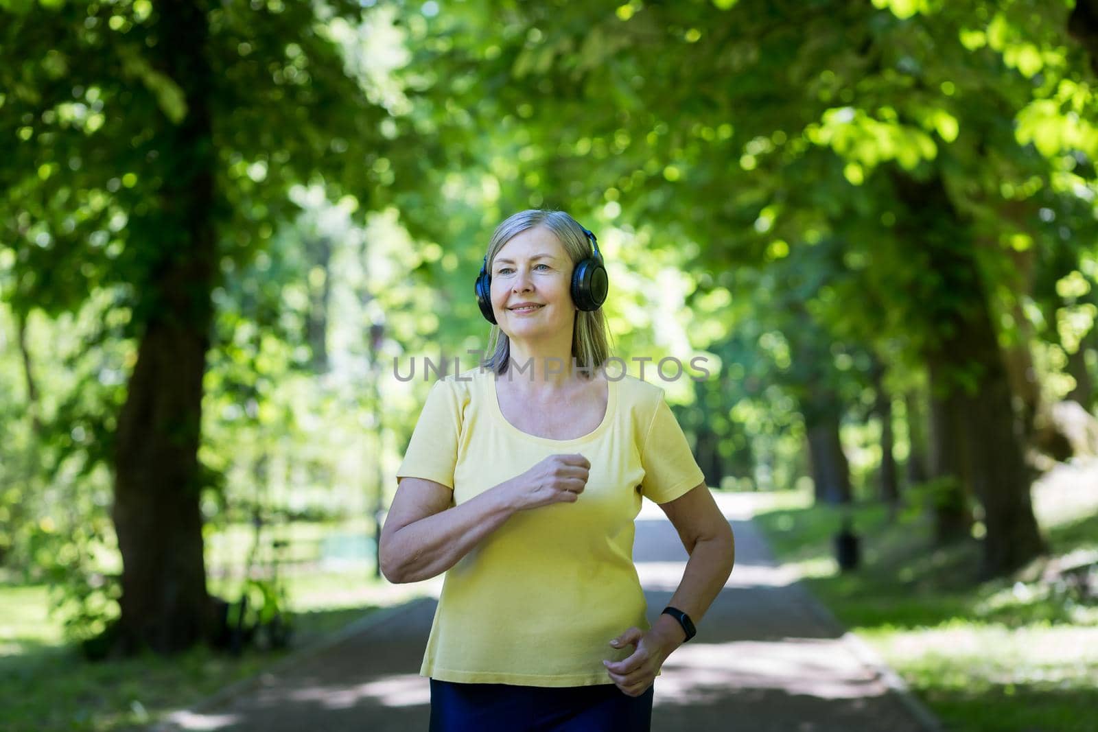 Senior gray-haired woman jogging in a summer park