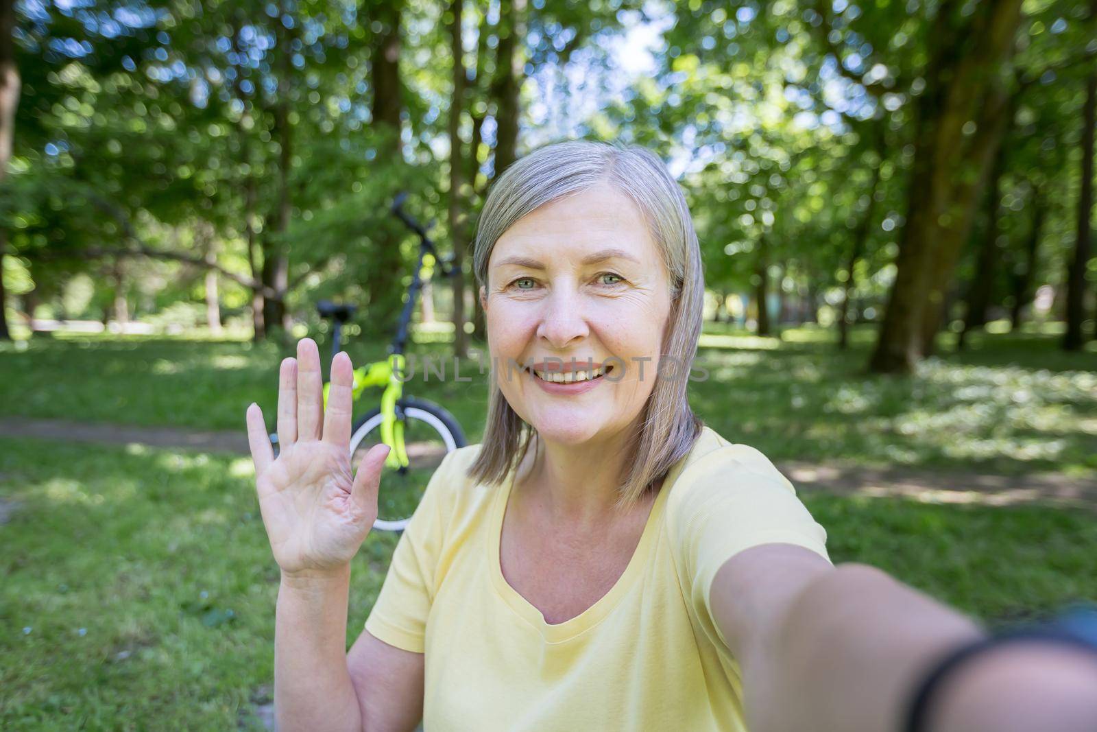 Senior active woman in the park talking on a video call, looking at the smartphone camera by voronaman