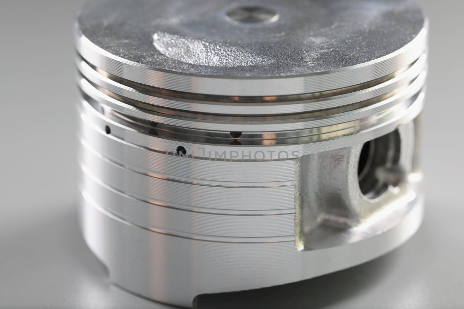 Close-up of silver metal part of car, detail for internal combustion engine placed on grey. Piston for automobile vehicle. Transport, component concept