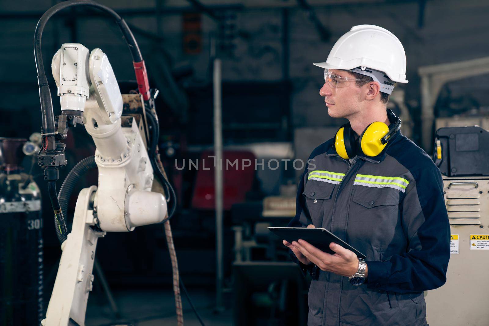Young factory worker working with adept robotic arm by biancoblue