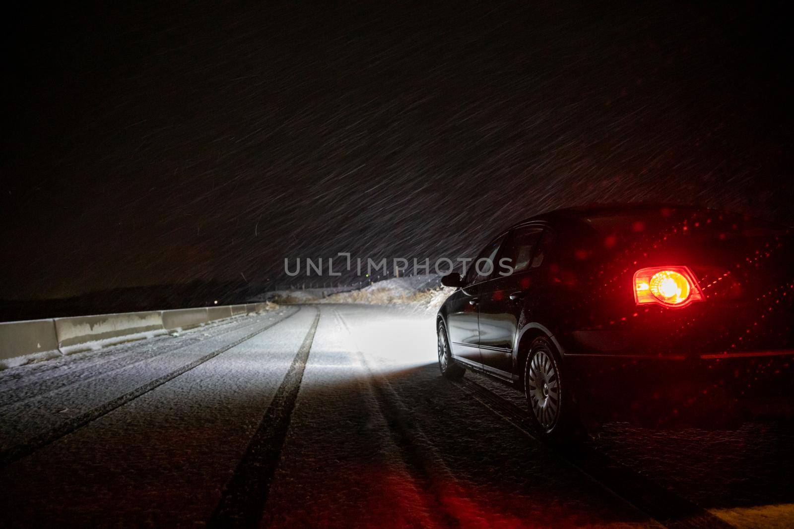 Car driving at night during a snow storm where it can be dangerous