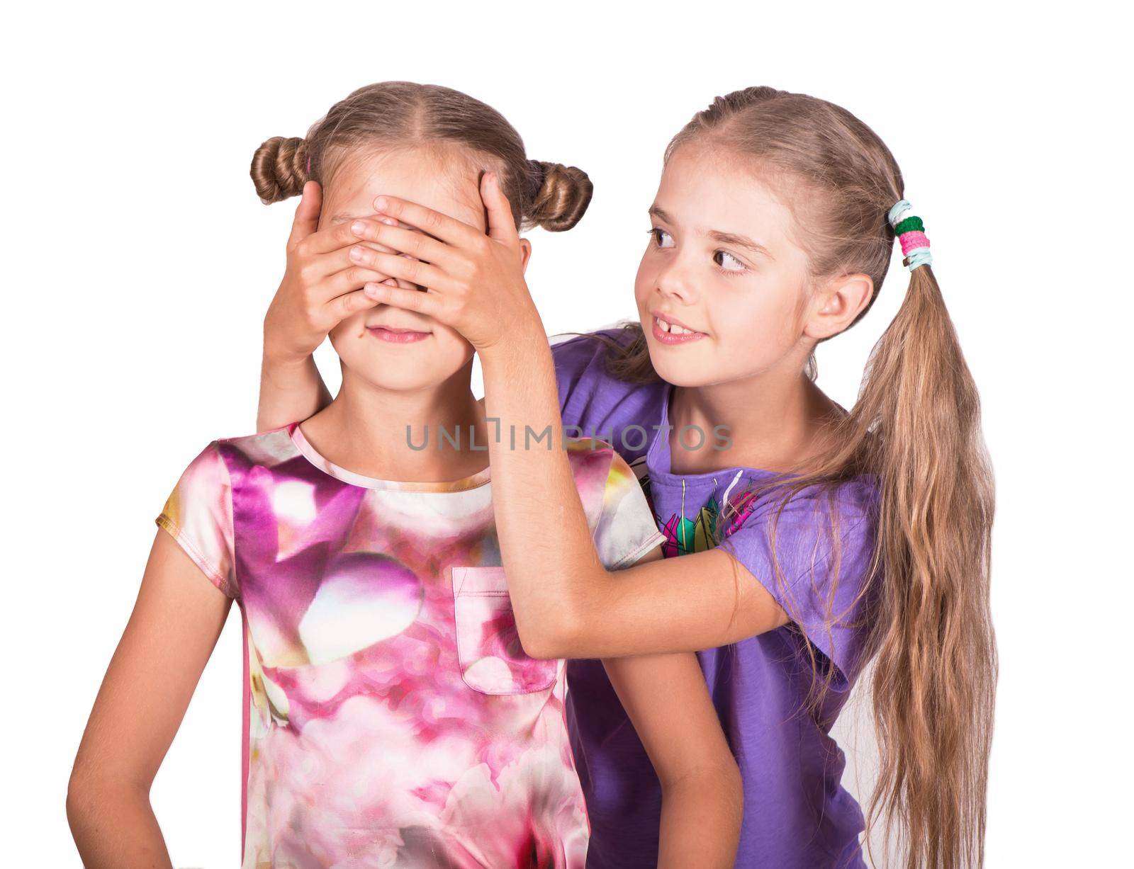 Children play and joke. One girl closes the eyes of another. Photo isolated on white background by aprilphoto