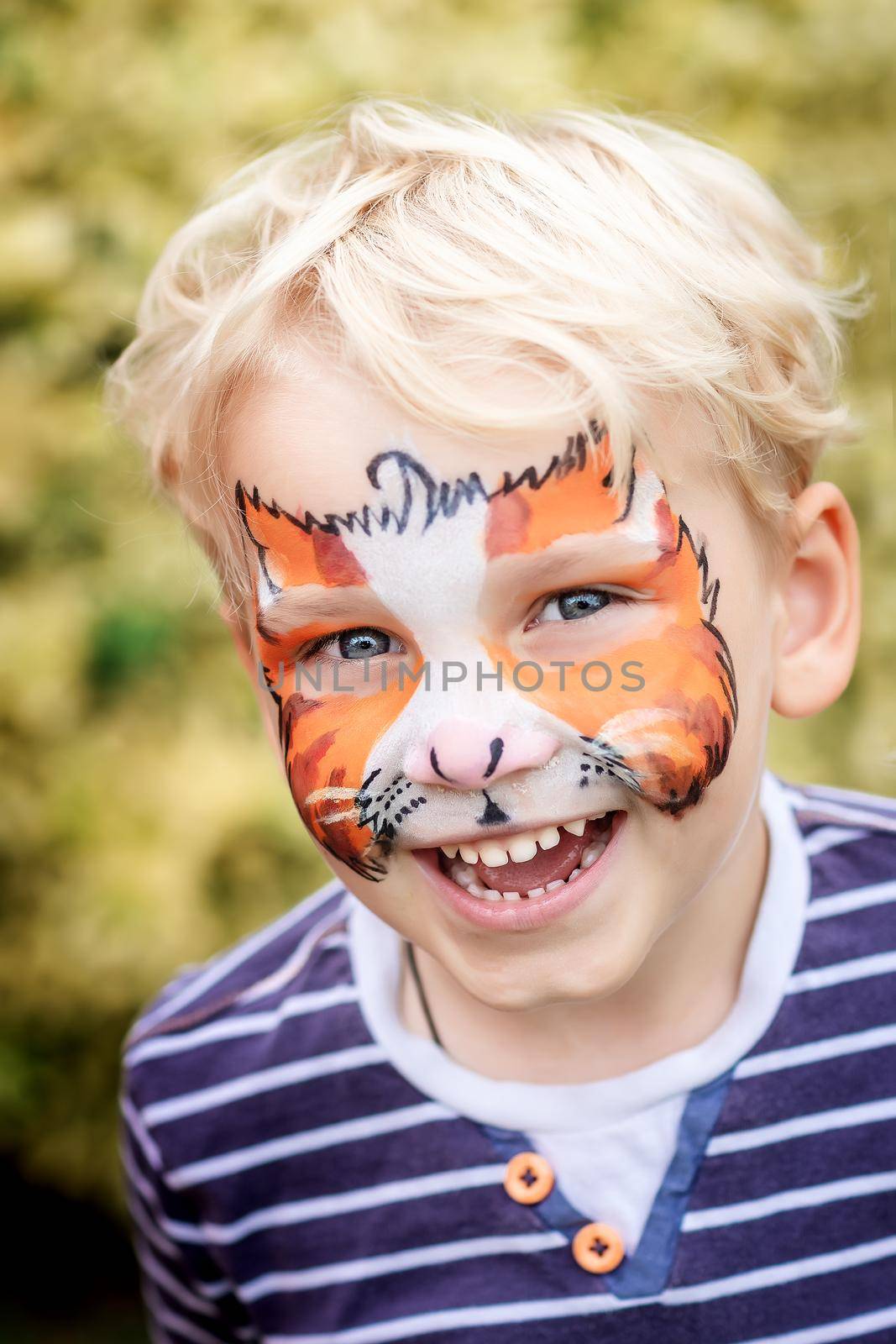 Cute happy and excited little boy with face paint. Face painting, kid painting face at the birthday party or on holidays