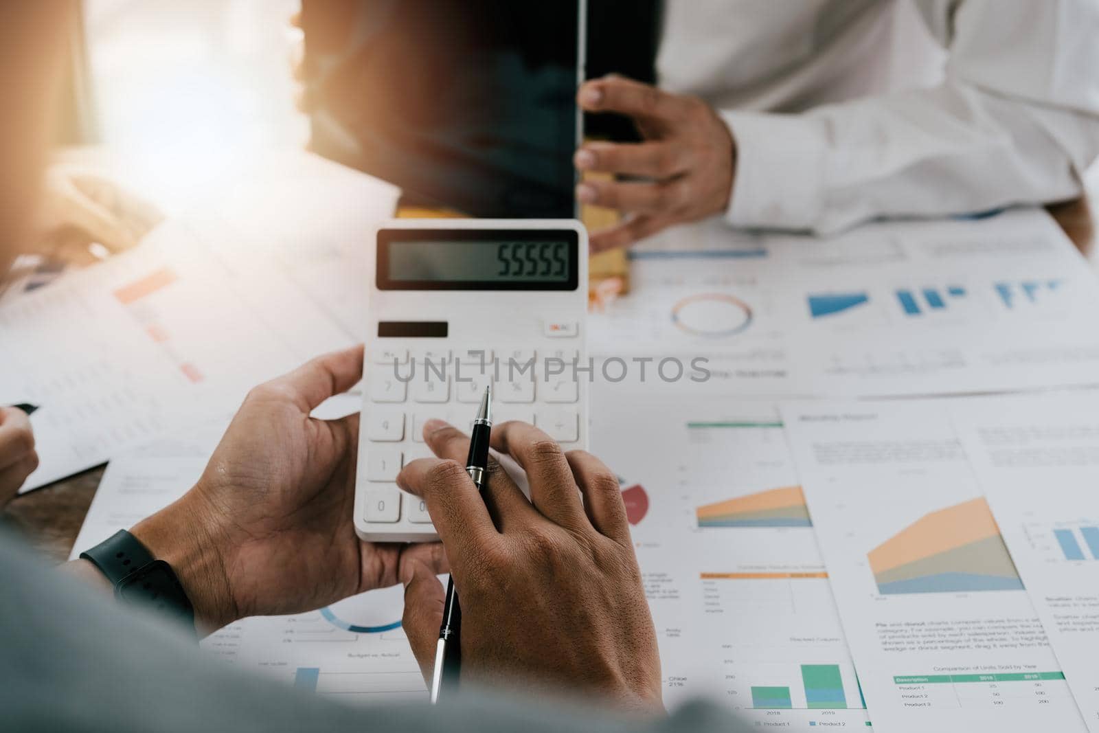 asian businessman or accountant working pointing graph discussion and analysis data charts and graphs and using a calculator to calculate numbers.Business finances and accounting concept.