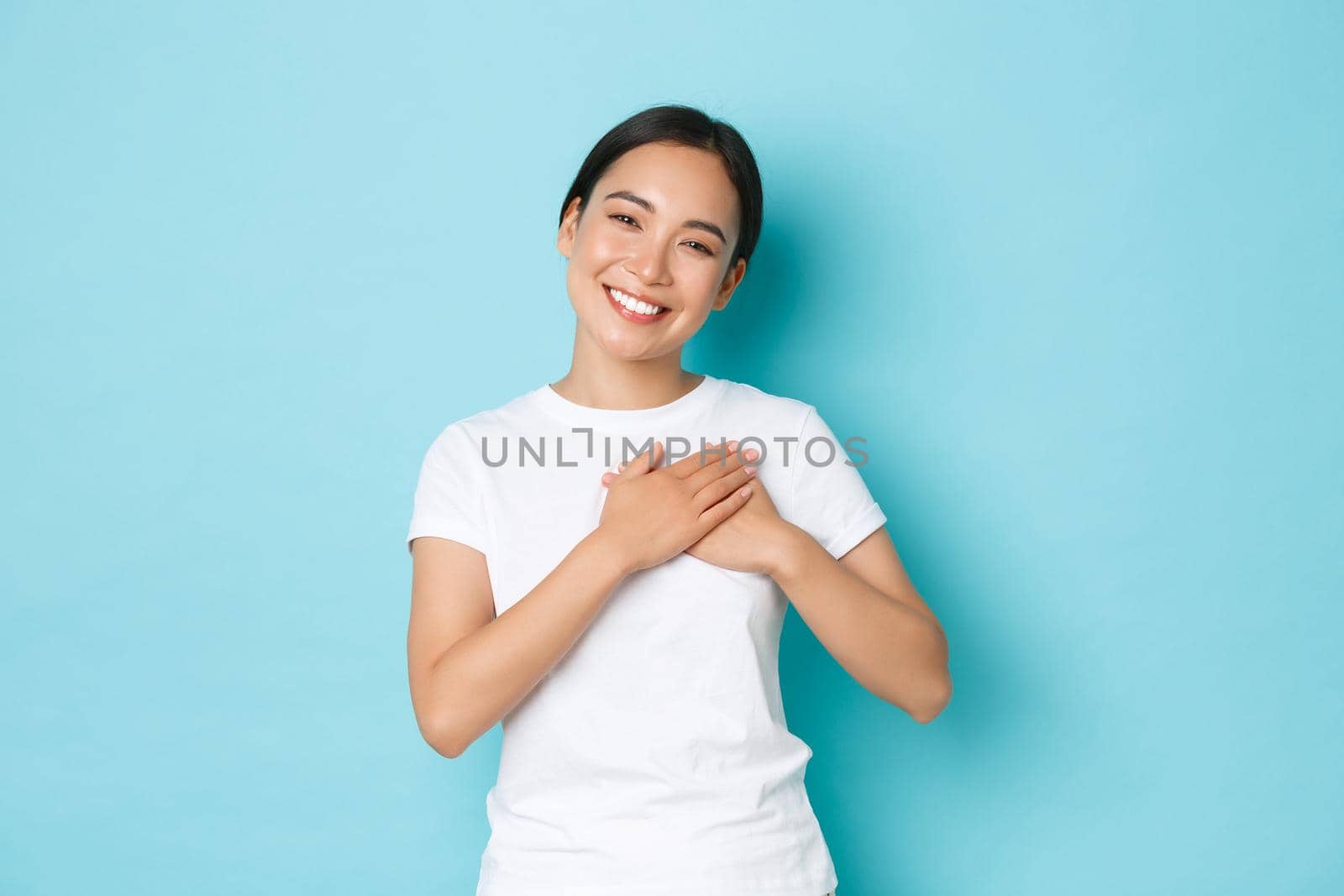 Lifestyle, beauty and shopping concept. Portrait of touched and grateful pretty asian girl thanking for flattering compliment, holding hands on heart and smiling with caring, tender expression by Benzoix