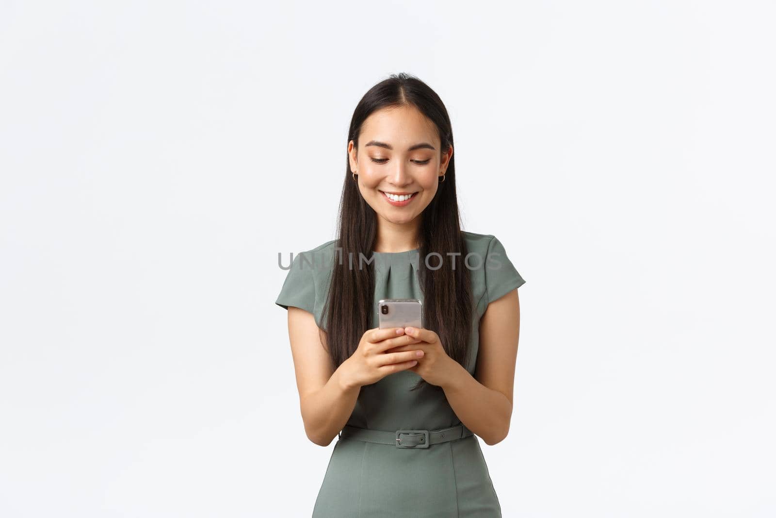 Small business owners, women entrepreneurs concept. Smiling young female running startup in internet, checking messages from clients, texting someone on mobile phone, using smartphone.
