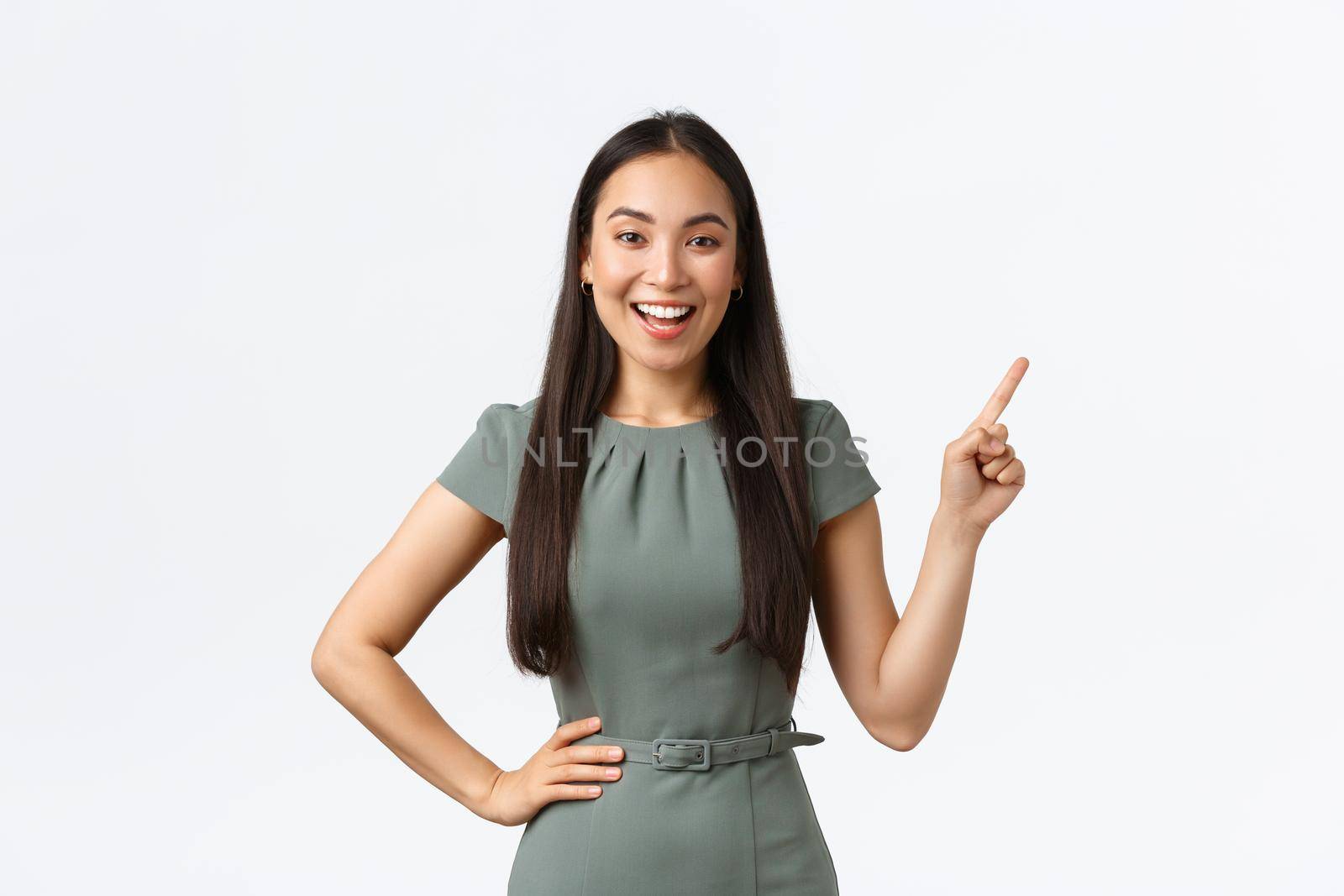Small business owners, women entrepreneurs concept. Smiling businesswoman showing her online store link, pointing finger upper right corner, making presentation, looking camera confident.