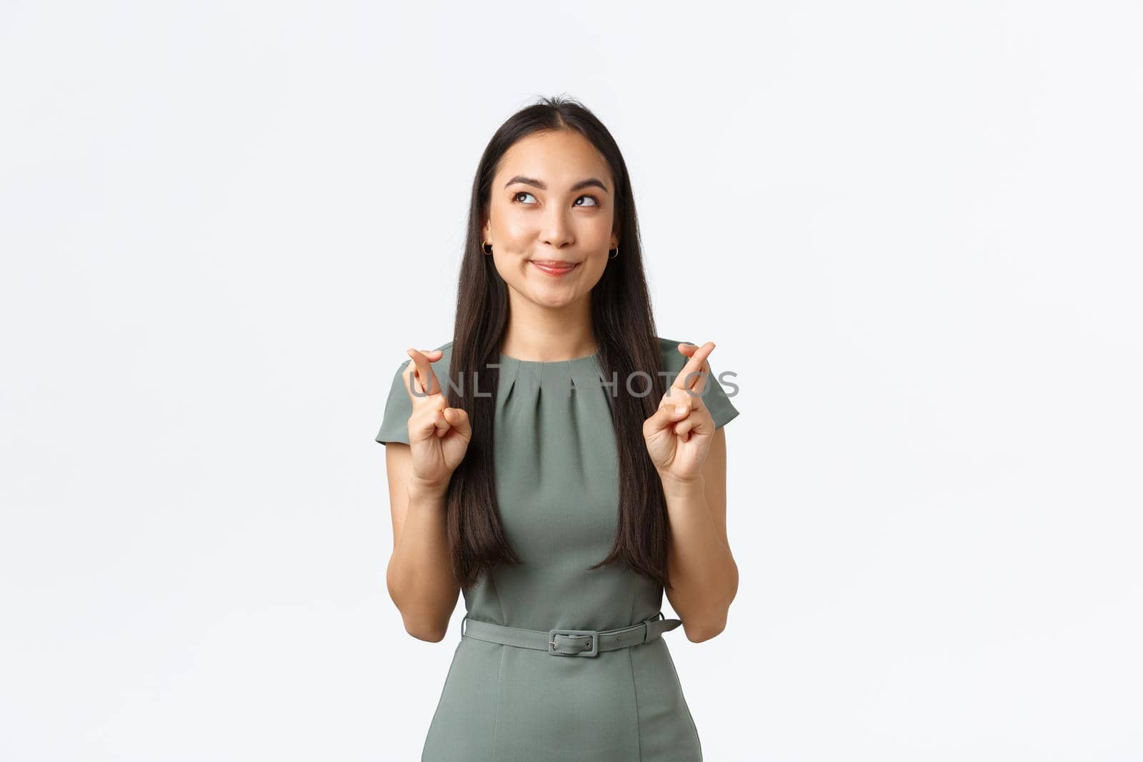 Small business owners, women entrepreneurs concept. Hopeful cute dreamy asian woman having faith, cross fingers good luck, smiling and looking upper left corner, imaging how dream come true.
