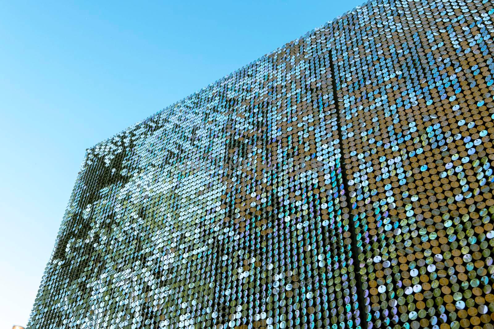 abstract background of silver disks suspended on strings and preserved by the wind. sparkling texture against a blue sky background