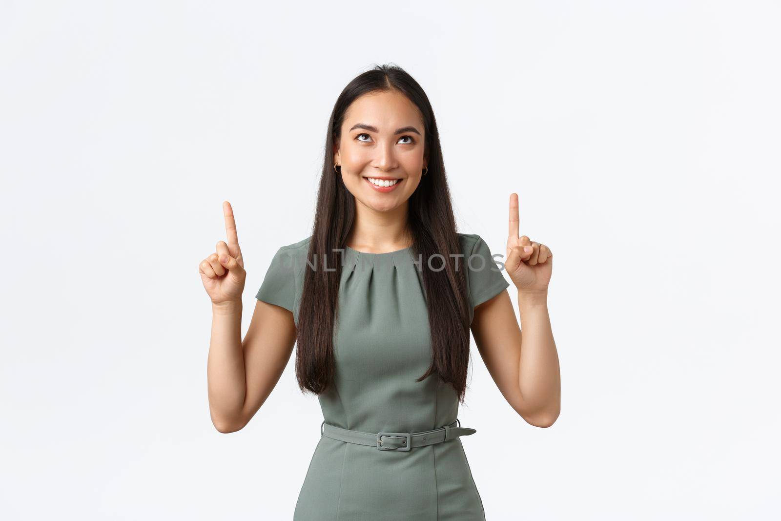 Small business owners, women entrepreneurs concept. Happy intrigued asian woman in dress pointing fingers up and looking tempting, want try something or buy at online store for special price by Benzoix