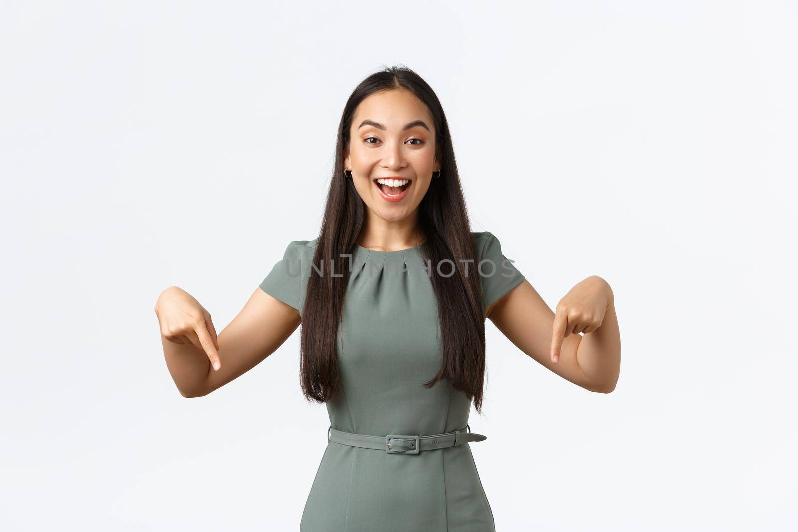 Small business owners, women entrepreneurs concept. Happy beautiful asian businesswoman inviting to check out promo, pointing fingers down at event banner, smiling at client, white background by Benzoix