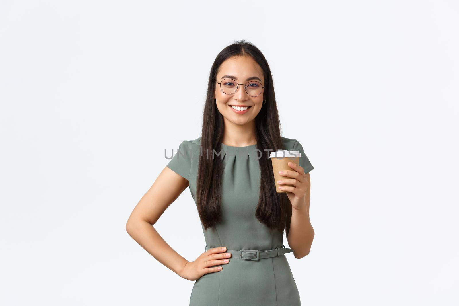 Smiling successful asian businesswoman in glasses standing confident, drinking morning coffee and starting new business day at office, manage own store from home, standing white background.