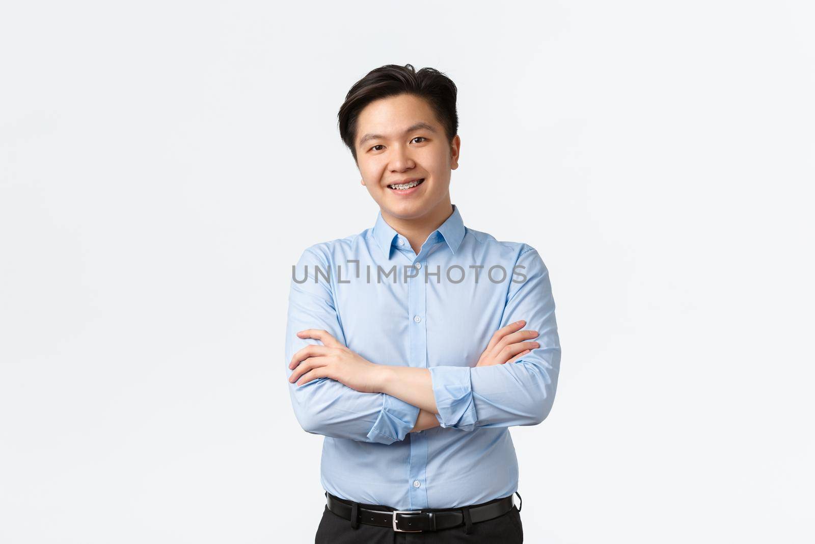 Business, finance and people concept. Professional confident asian businessman with teeth braces, smiling pleased, cross arms chest, standing white background, Salesman showing product.
