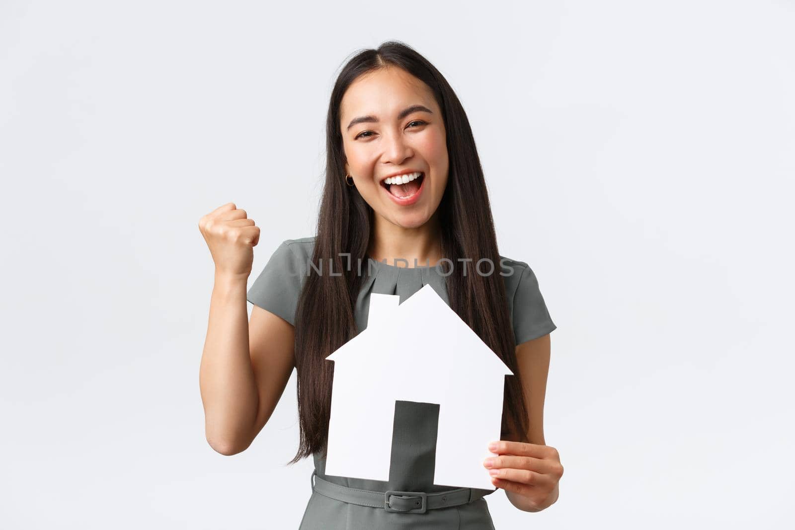 Insurance, loan, real estate and family concept. Successful winning asian female broker, saleswoman selling another apartment and feeling rejoice, fist pump say yes and showing paper house by Benzoix