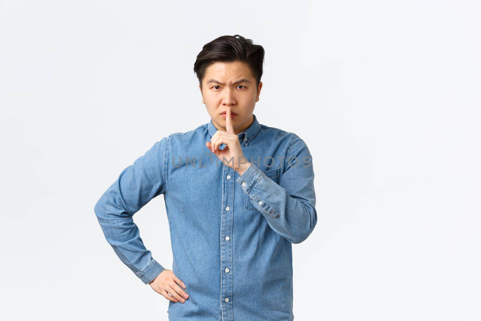 Angry asian man, teacher shushing at disobedient student, looking displeased. Man scolding person being too loud, shushing, say shh with finger pressed to lips, tell stay silent, white background by Benzoix