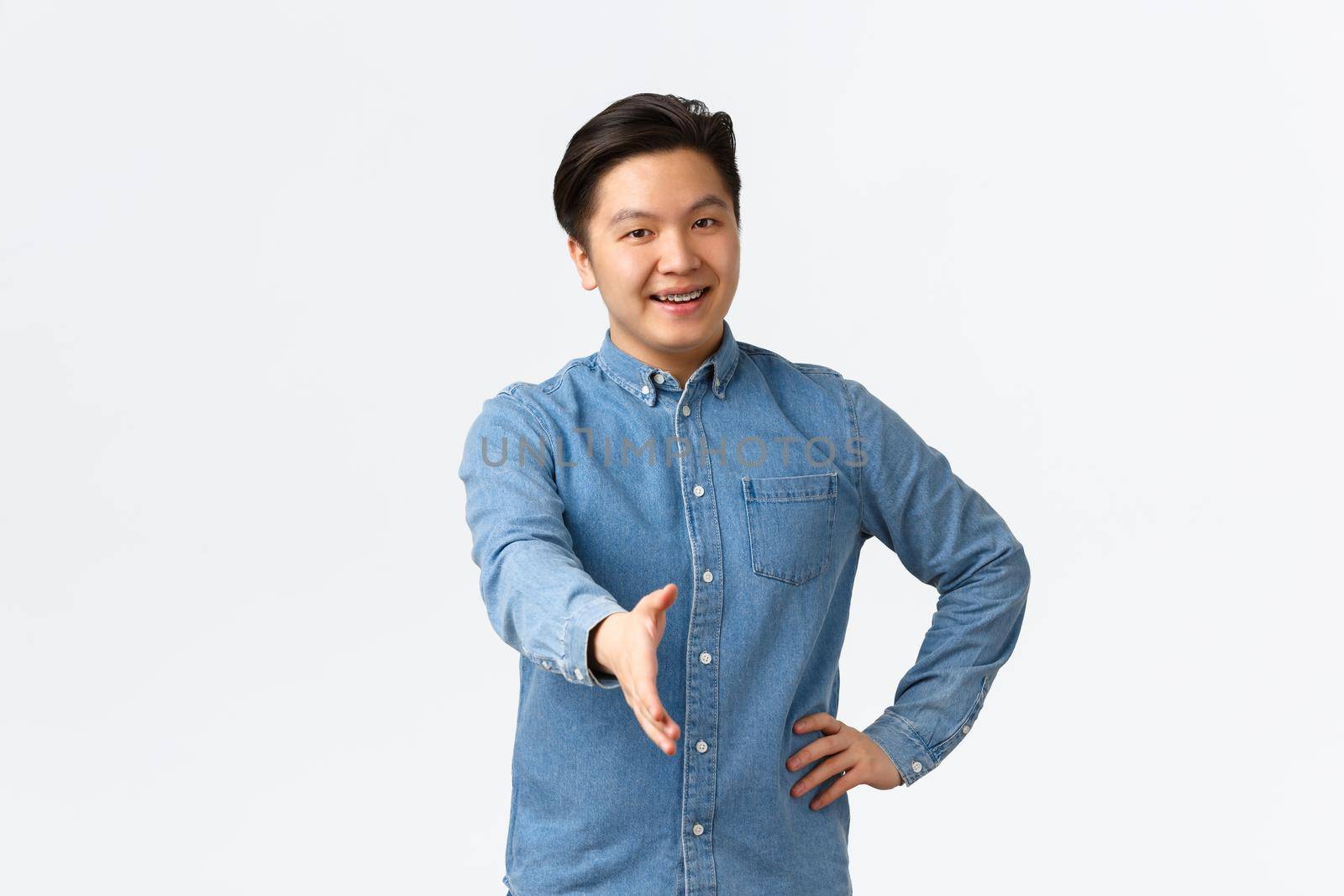 Friendly cheerful asian man searching for job, come to interview, extending hand for handshake, greeting someone, welcome to office, saying hello with happy smile, white background.