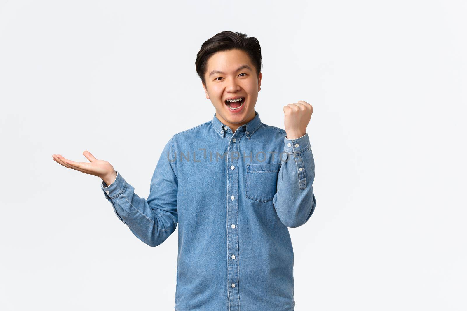 Successful winning asian male freelancer, guy fist pump holding something on hand over black white space, achieve item, receive product he wanted, celebrating or triumphing by Benzoix